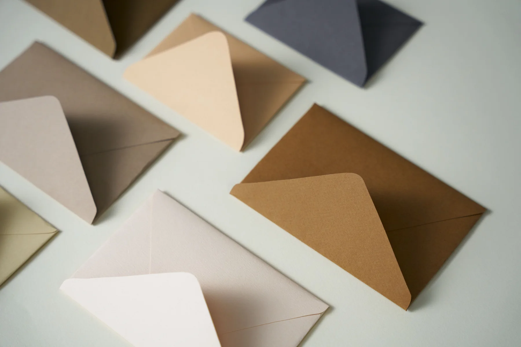 Umschläge in Beige und Braun, aufgefächert auf hellem Grund.
